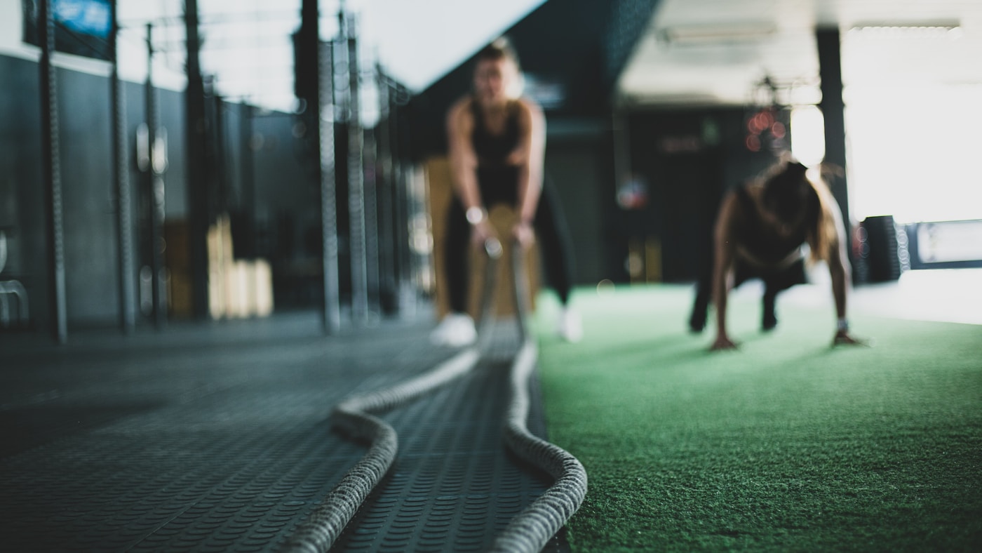 Two people working through a conditioning session on a gym floor